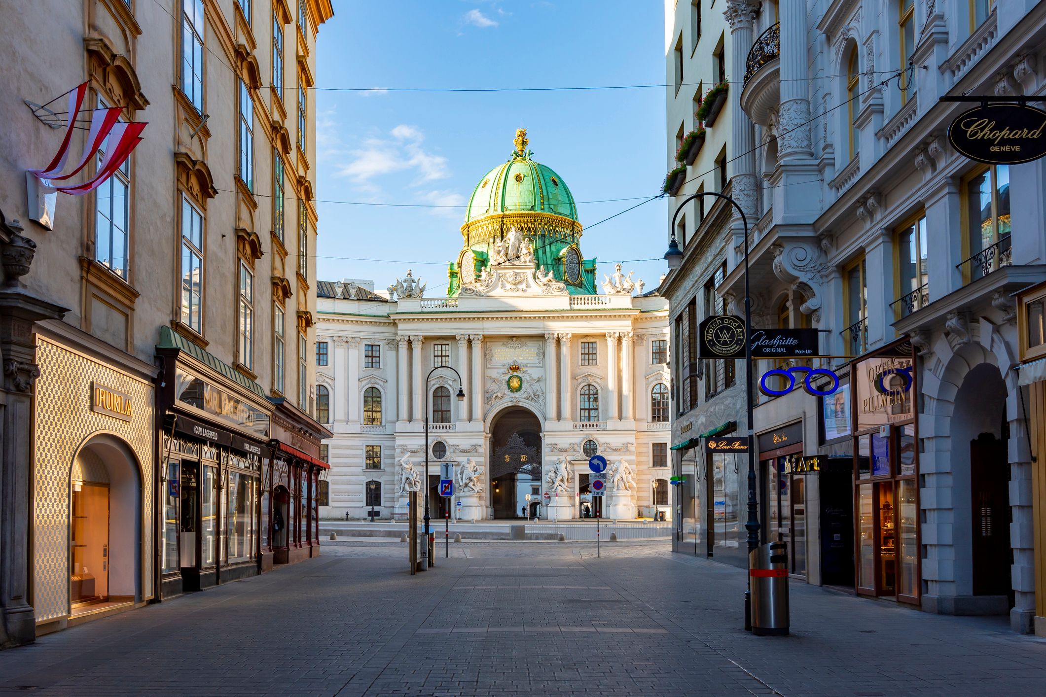 Blick auf einen Eingang der Hofburg von einer Gasse aus bei Sonne