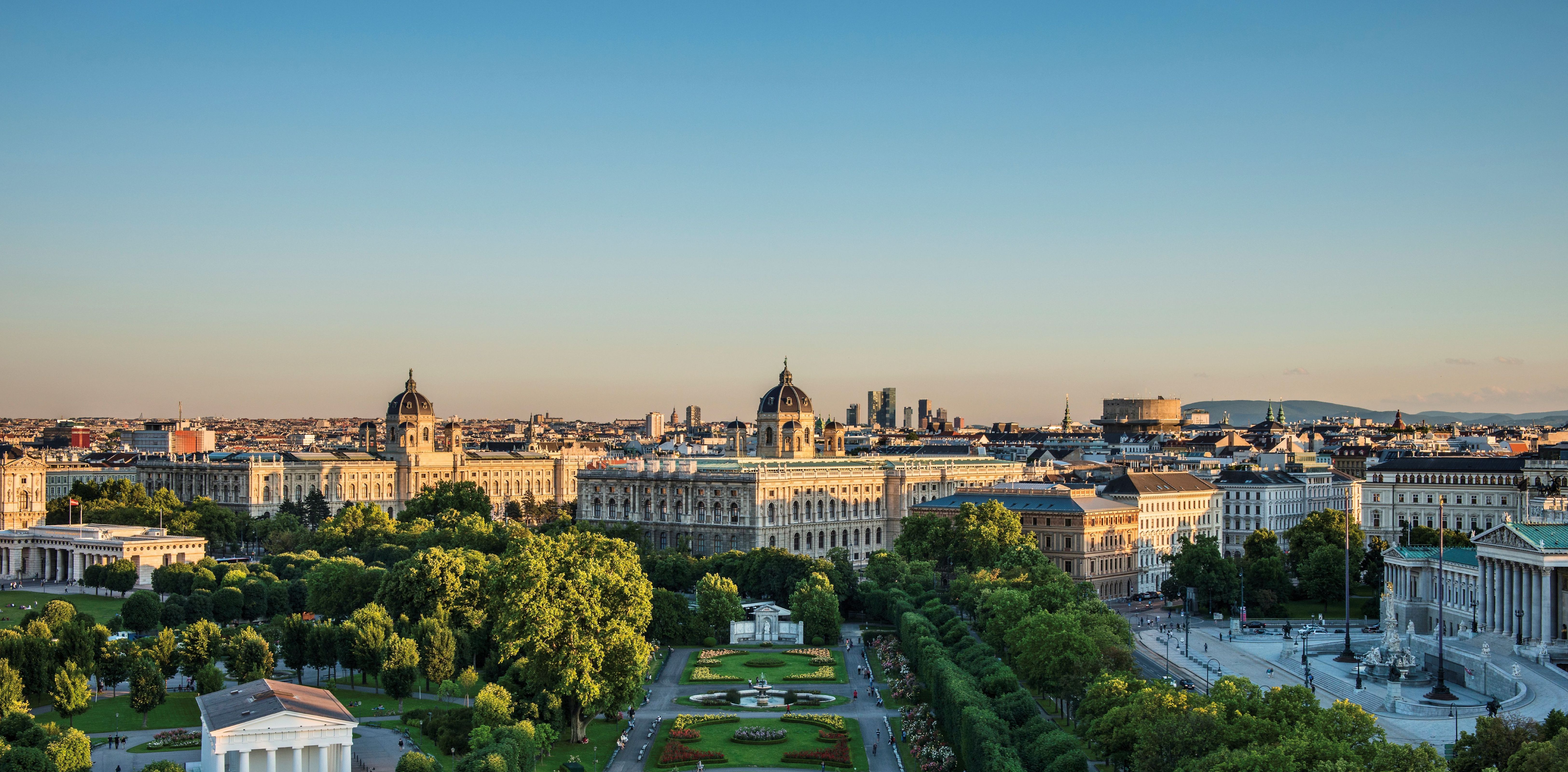 Panoramablick auf den grünen Volksgarten und Häuser Wiens während dem Sonnenuntergang