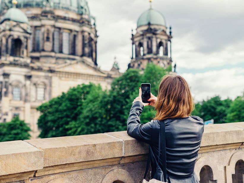 eine junge Frau macht mit ihrem Handy ein Foto vom Berliner Dom