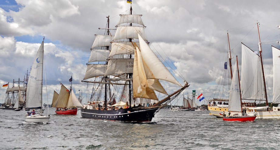 Einlaufparade während der Kieler Woche mit vielen Segelschiffen vor grau bewölktem Himmel - BAHNHIT.DE, © getty