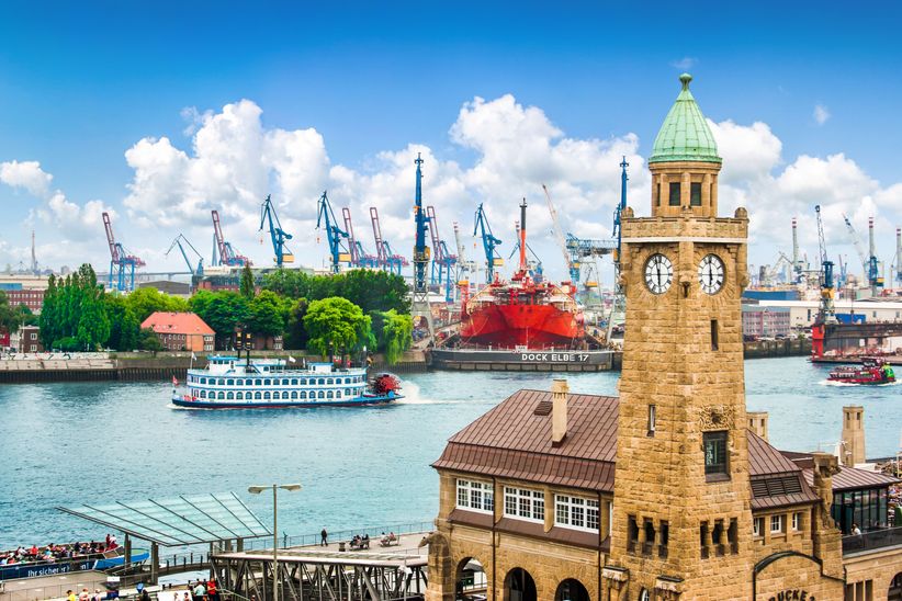 Pegelturm am Hamburger Hafen mit Schiff und Ladekränen im Hintergrund