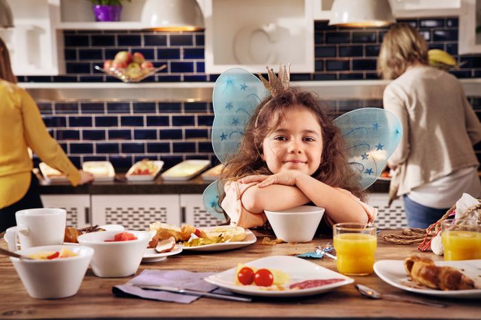 Mädchen sitzt am Tisch und isst Frühstück im Premier Inn Hotel, umgeben von gemütlicher Atmosphäre und modernem Interieur.