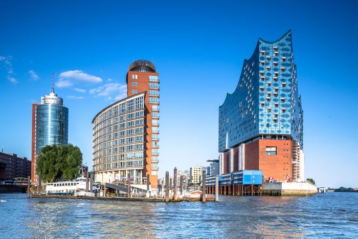Hamburger Elbphilharmonie und zwei weitere Gebäude am Hafen bei blauem Himmel