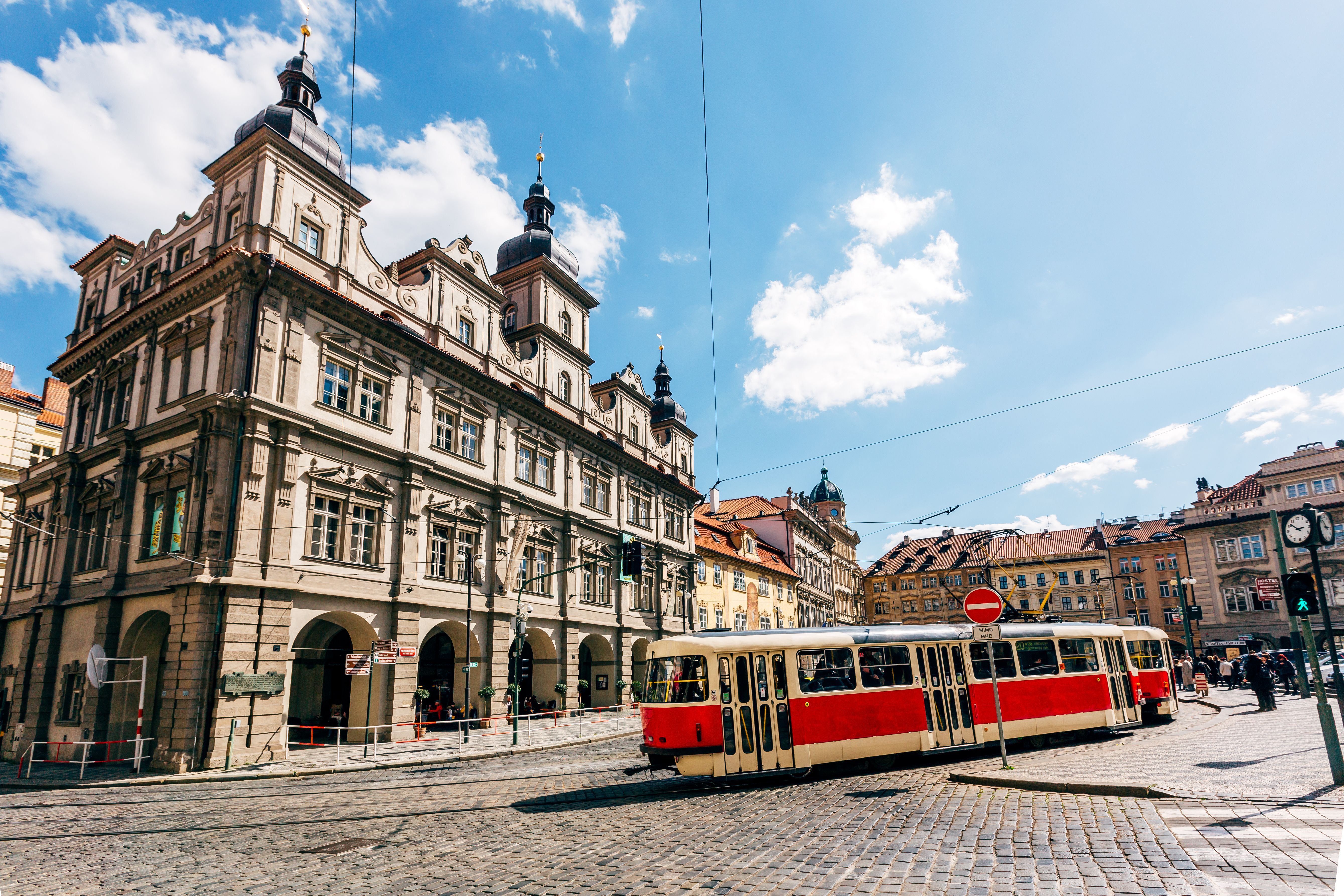 Rote Straßenbahn in Prag, fährt vor einer Kulisse aus historischen Gebäuden durch die Stadt.