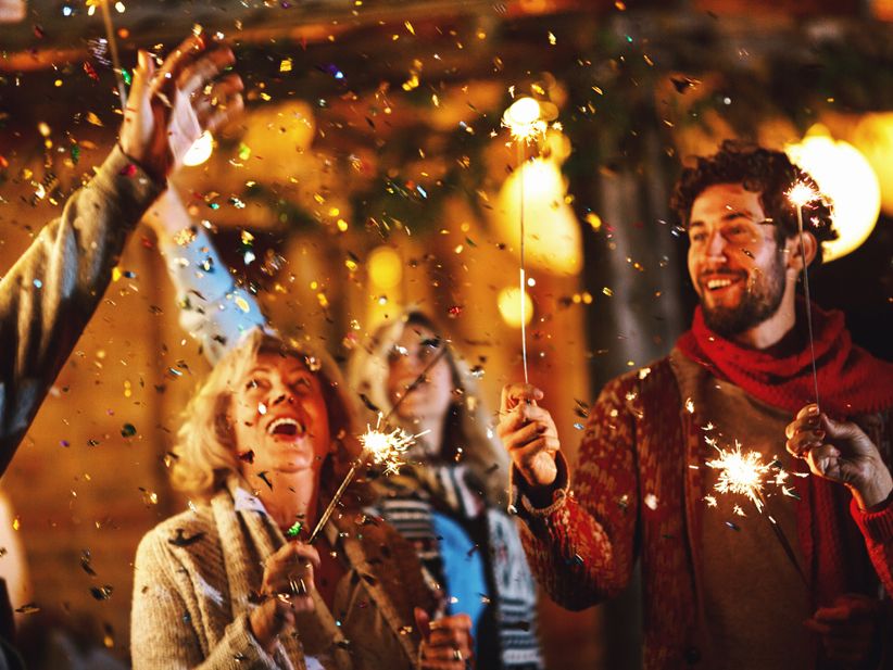 Menschen feiern Silvester mit Wunderkerzen im Freien bei Nacht