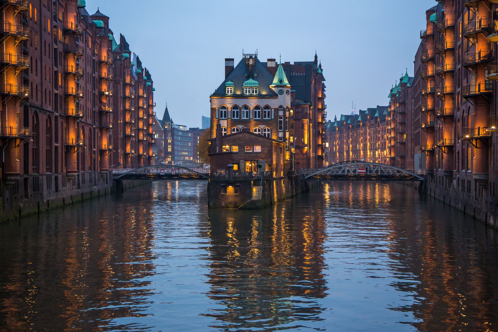 Beleuchtete Hamburger Speicherstadt mit zwei Kanälen um ein Gebäude am Abend
