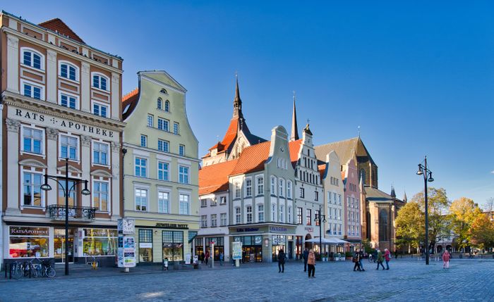 Blick auf den Marktplatz in Rostock mit dem historischen Rathaus und bunten Giebelhäusern.
