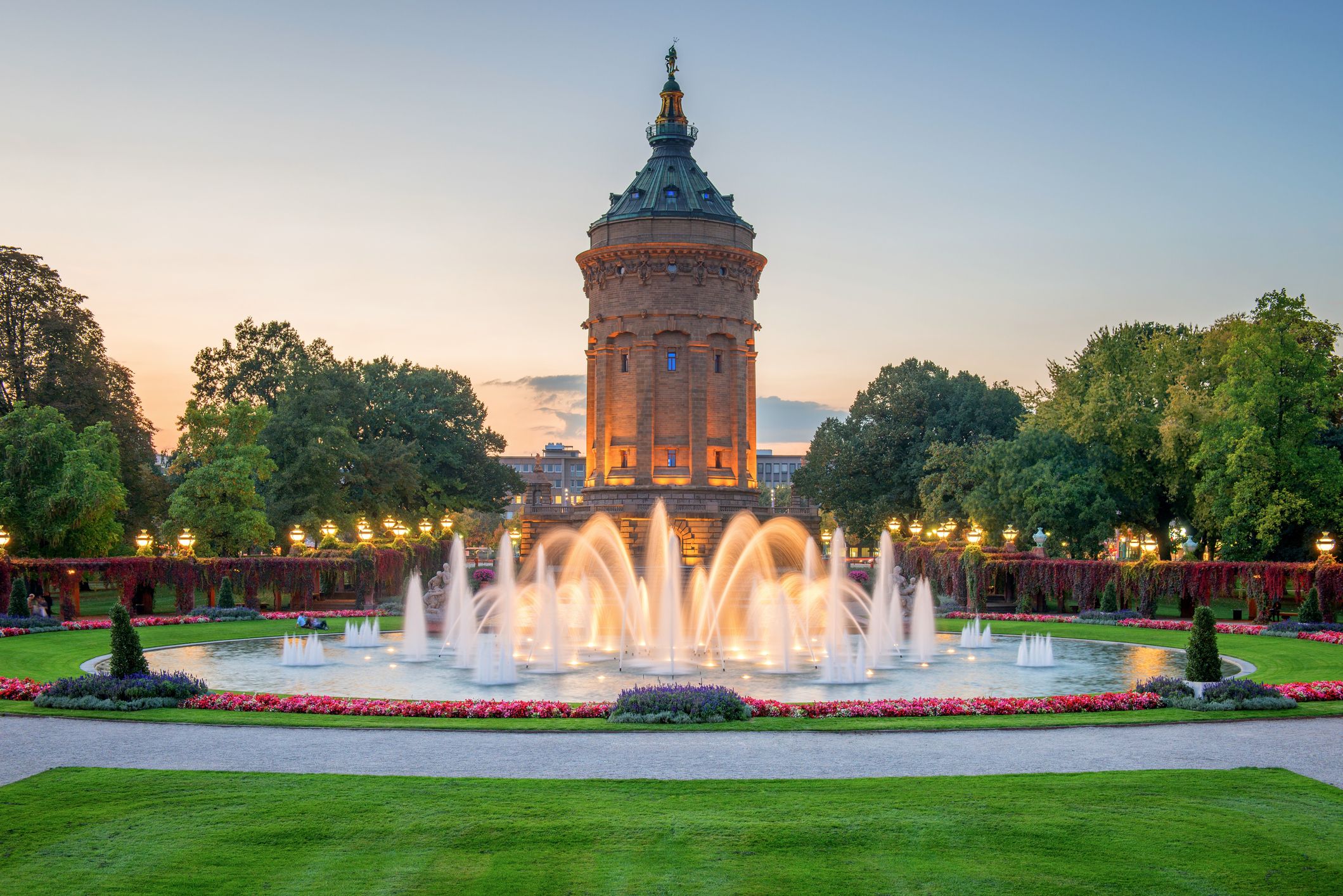 Beleuchtetes Wasserspiel im Brunnen vor dem beleuchteten Wasserturm in Mannheim am Abend
