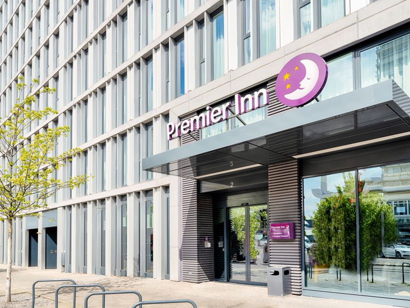 Eingangsbereich des Premier Inn Hotels mit automatischen Glastüren und beleuchtetem Logo über dem Eingang