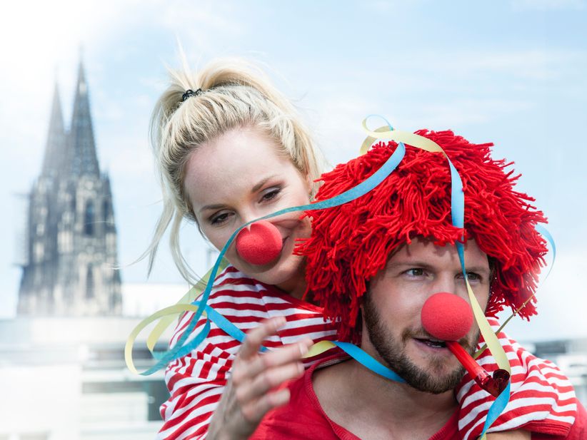 ein Paar verkleidet zum Kölner Karneval mit dem Kölner Dom im Hintergrund