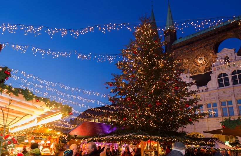 Weihnachtsmarkt in Lübeck mit beleuchteten Ständen und historischen Gebäuden im Hintergrund