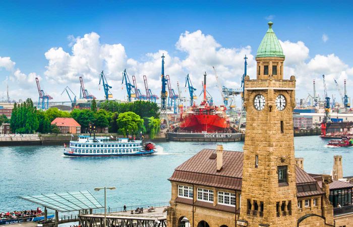Turm am Wasser mit Hafenkränen im Hintergrund