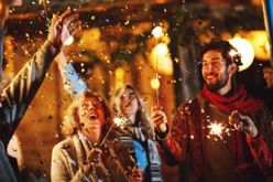 Menschen feiern Silvester mit Wunderkerzen im Freien bei Nacht