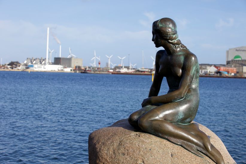 Statur der kleinen Meerjungfrau auf einem Stein sitzend mit dem Kanal im Hintergrund in Kopenhagen