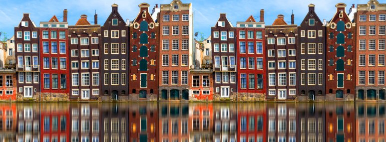 Aneinanderreihung traditioneller Häuser in Amsterdam und ihre Re­fle­xi­on im Wasser - BAHNHIT.DE, © getty, Foto: 2018 George Pachantouris