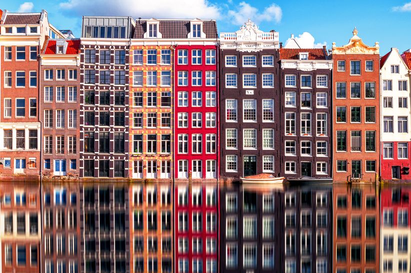 Blick auf eine Amsterdamer Gracht mit traditionellen Giebelhäusern entlang des Ufers.