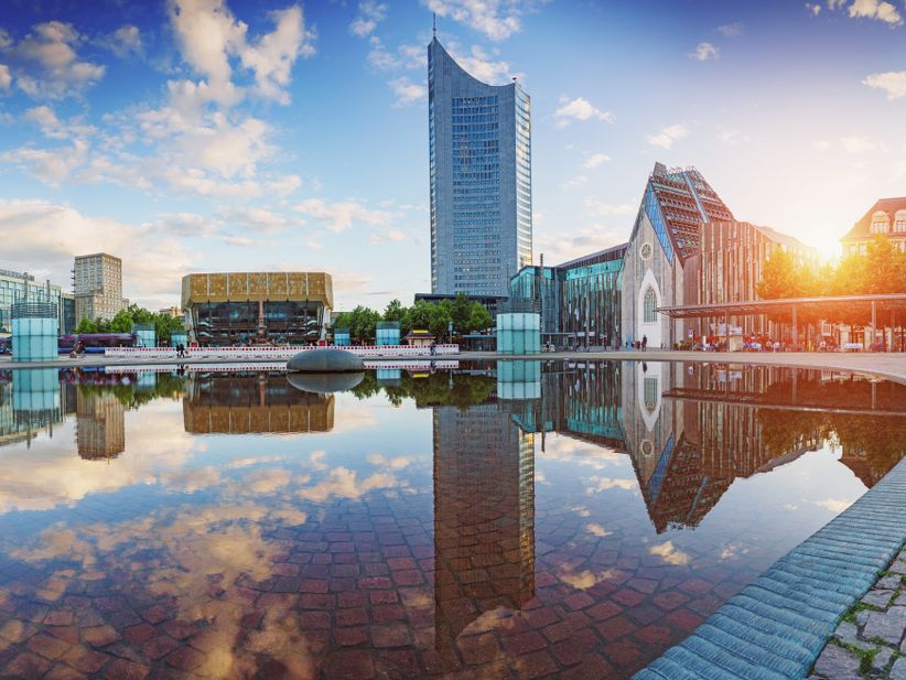 Gebäude spiegeln sich im Wasser am Augustusplatz in Leipzig