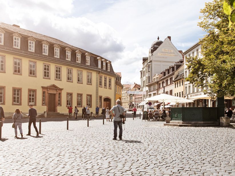 Außenansicht von Goethes klassizistischem Wohnhaus am Frauenplan in der Innenstadt von Weimar, umgeben von Kopfsteinpflaster und Passanten.