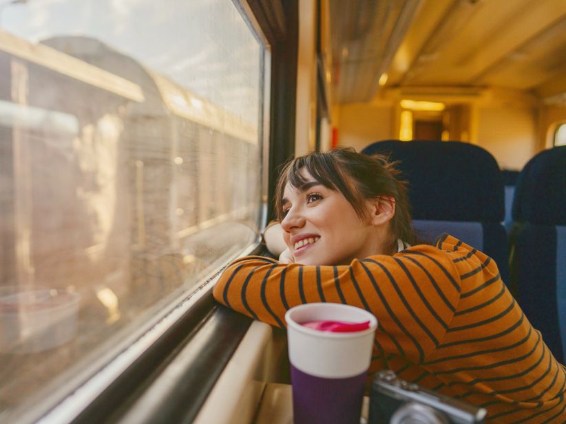 Frau lächelt beim Blick aus dem Zugfenster
