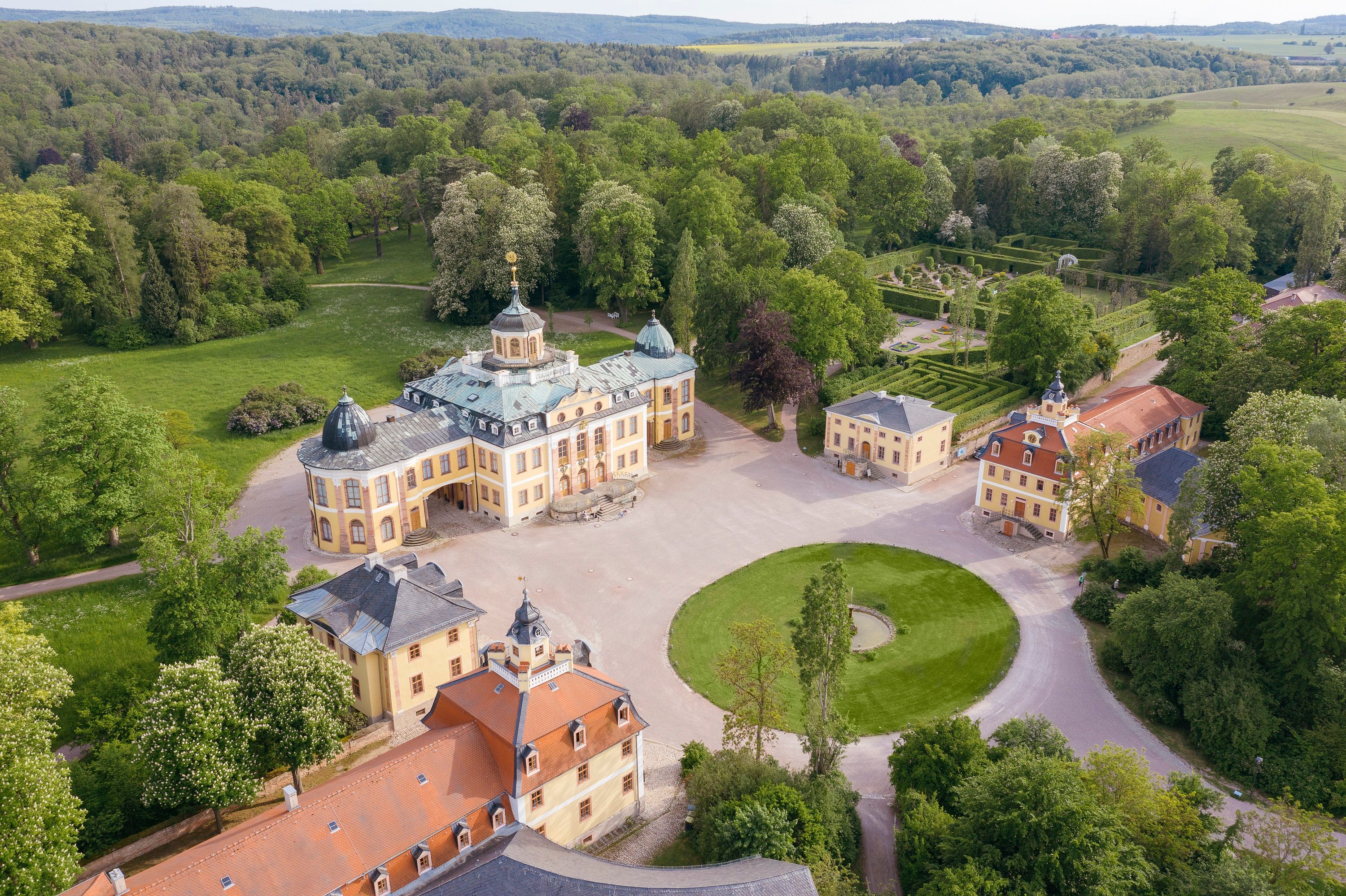 Schloss Belvedere bei Weimar aus der Vogelperspektive, umgeben von barocker Gartenanlage, symmetrischen Wegen und dichtem Grün des umliegenden Parks.