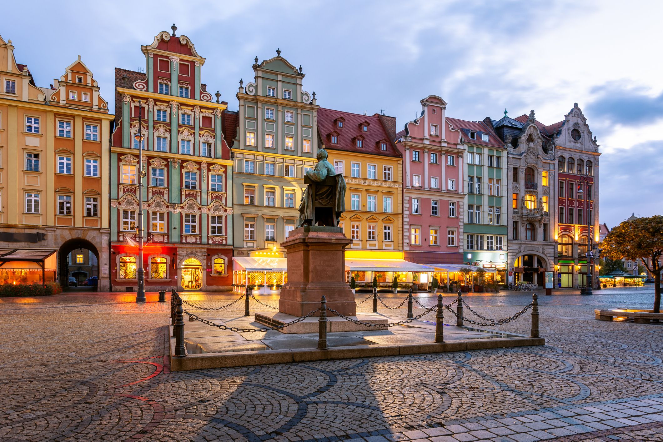 Breslau Marktplatz am Abend mit dem Aleksander Dredro Denkmal und beleuchtete Gastronomie im Hintergrund