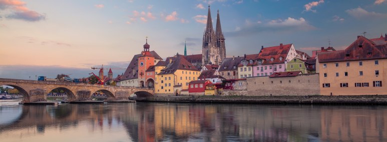 Regensburger Altstadt in der Dämmerung vom Wasser aus aufgenommen - BAHNHIT.DE, © getty, Foto: RudyBalasko