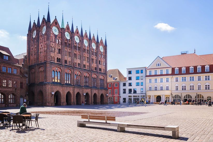 Das gotische Rathaus von Stralsund mit seiner markanten Backsteinfassade, umgeben vom historischen Marktplatz mit Kopfsteinpflaster und umliegenden Bürgerhäusern.