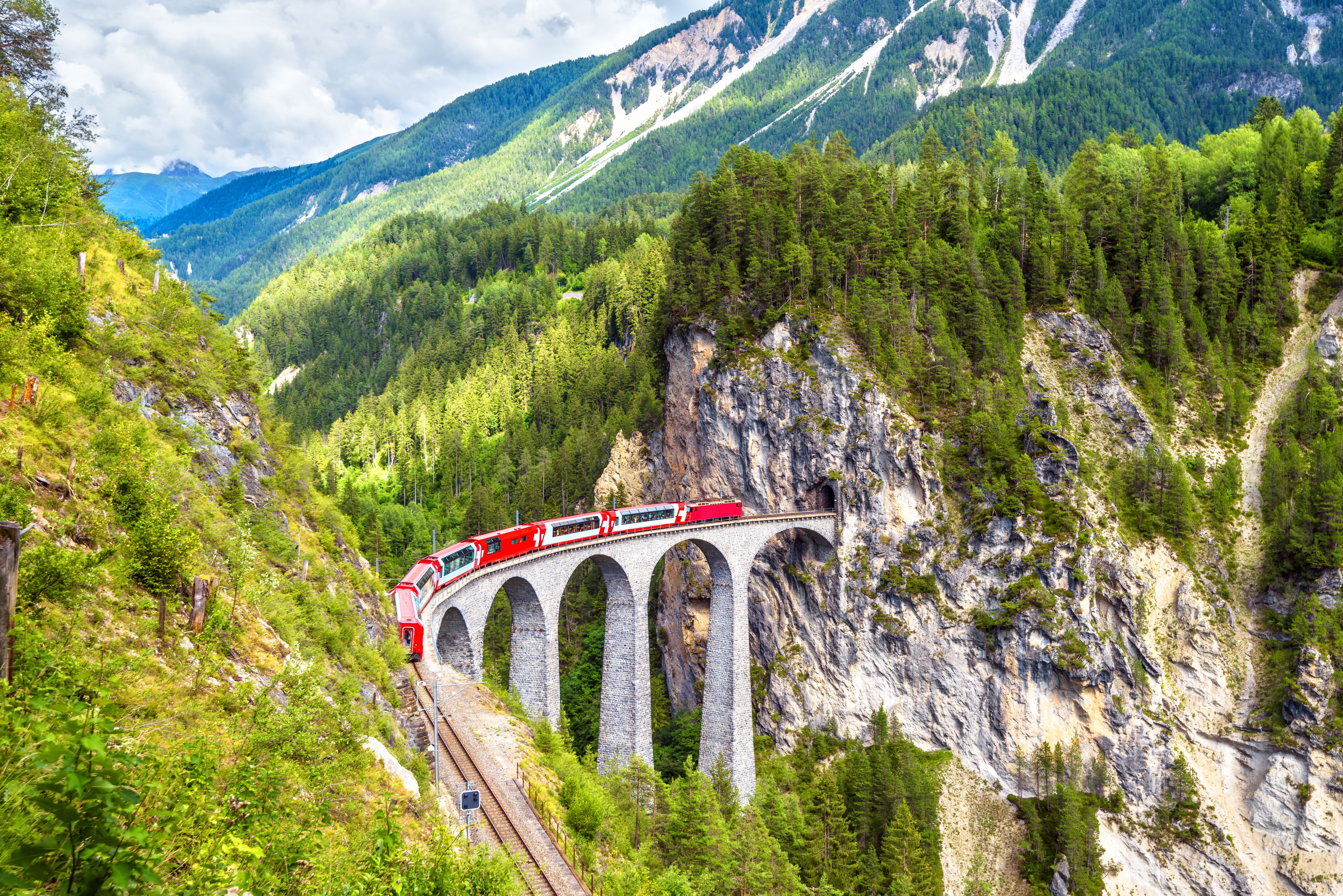 Zug fährt über Viadukt inmitten eines Shweizer Bergpanoramas