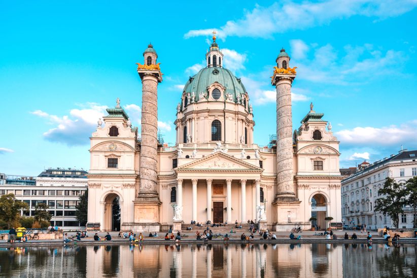 Menschen vor der Karlskirche in Wien bei blauem Himmel
