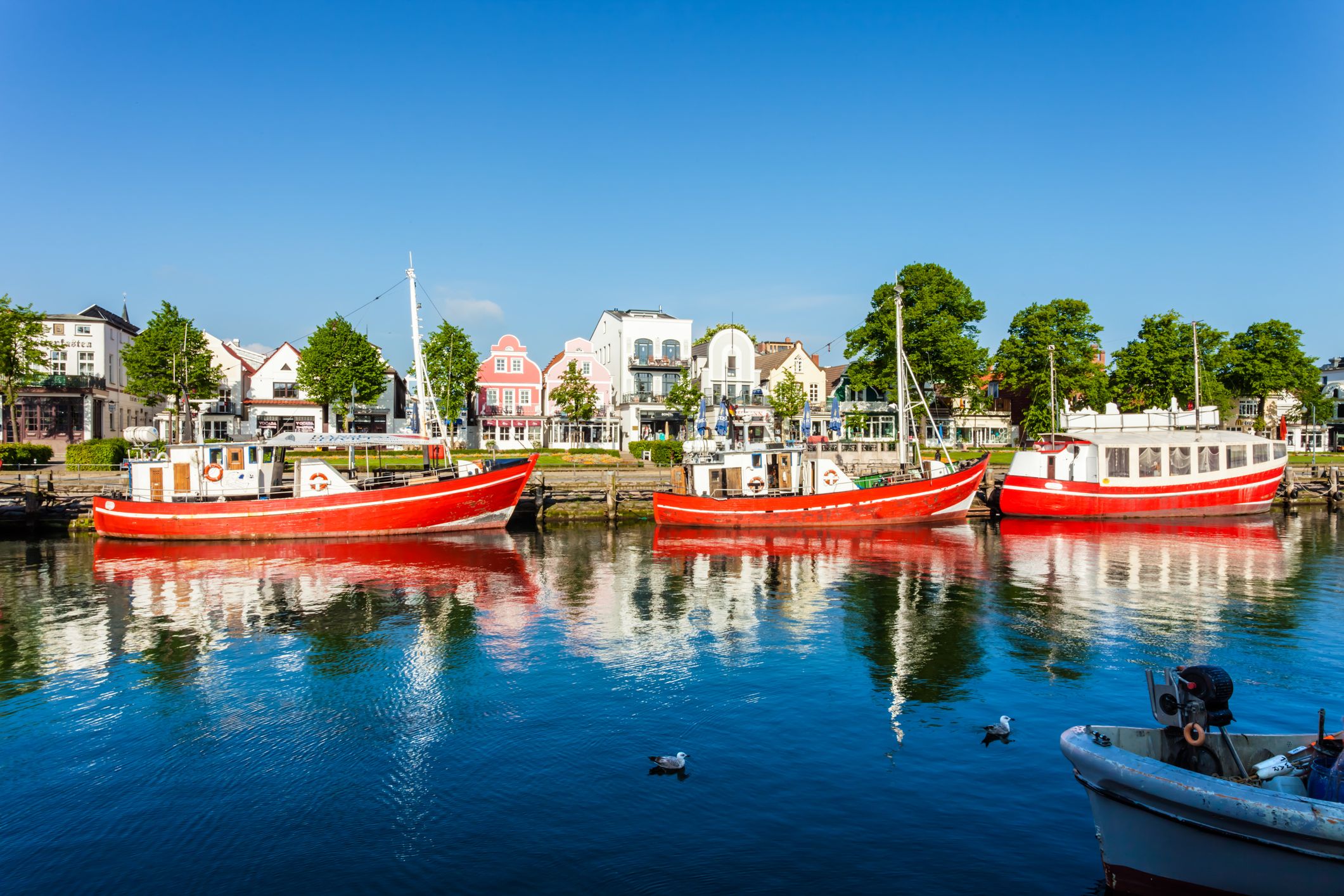 Warnemünde mit Booten im Alten Strom und Blick auf die historischen Häuser entlang der Uferpromenade.