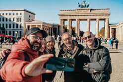 Reisegruppe schießt vor dem Brandenburger Tor in Berlin ein Selfie