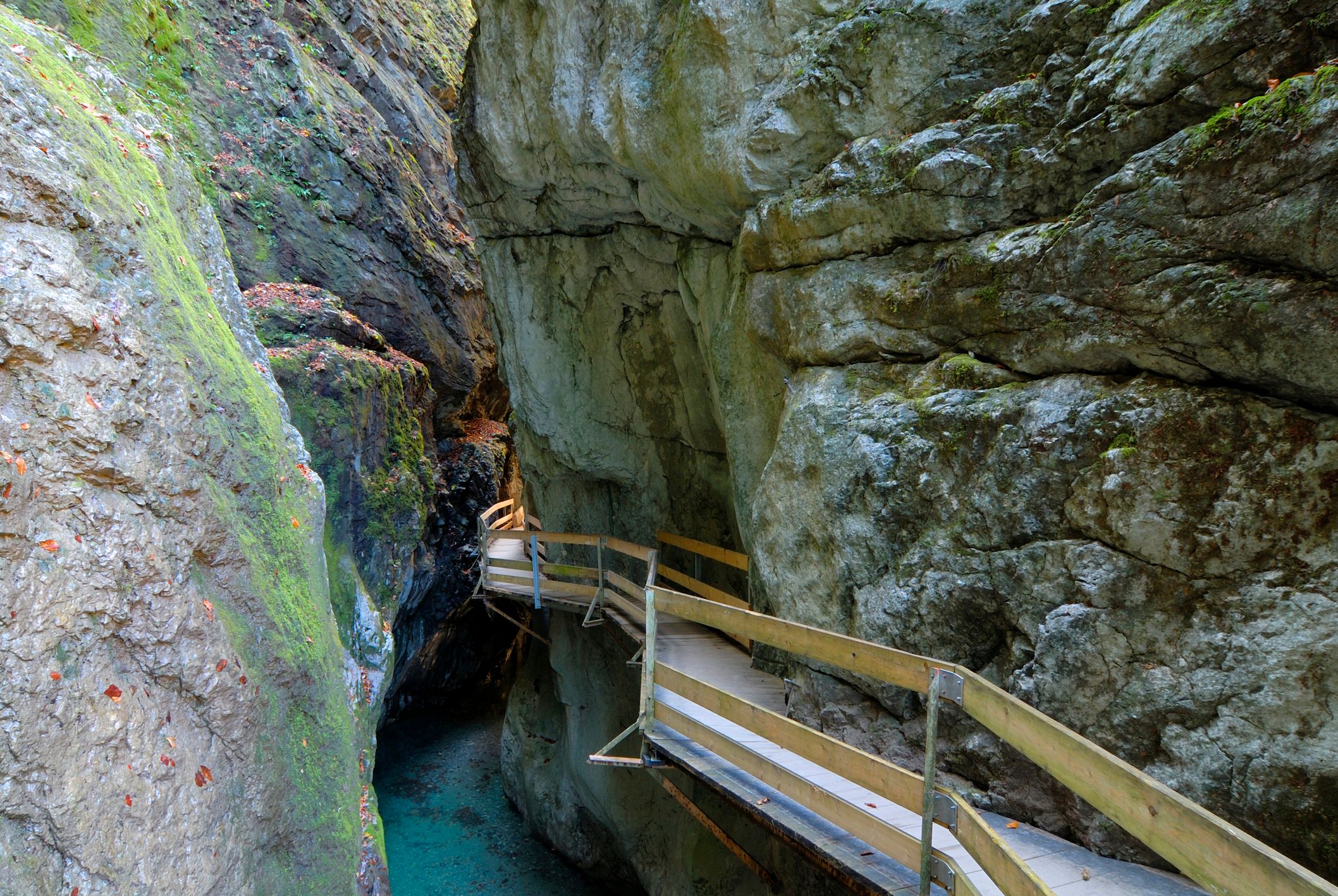 Schmaler Holzweg an einer Felsenwand über Wasser in der Rappenlochschlucht in Dornbirn