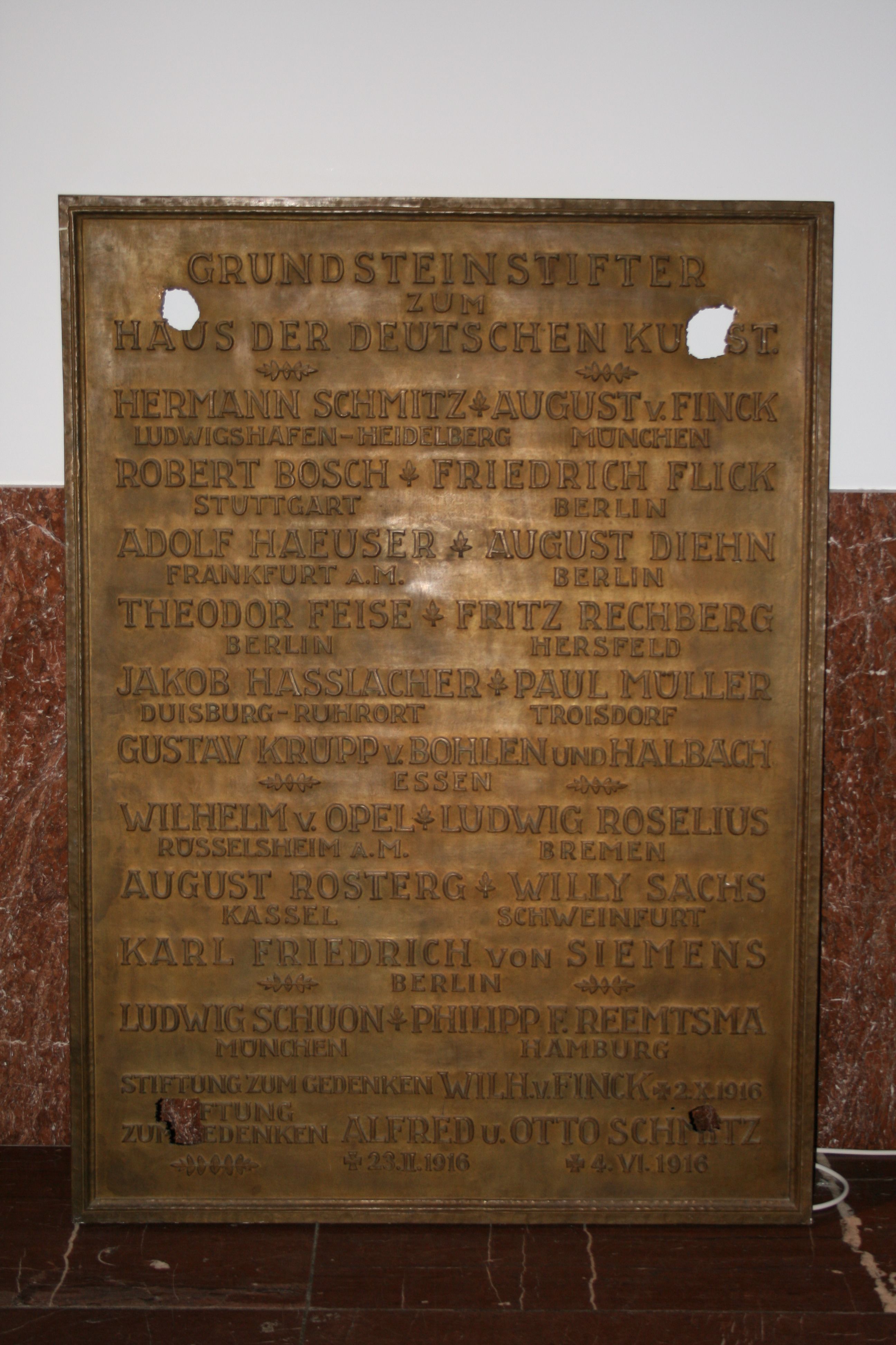 Bei dem abgebildeten Gegenstand handelt es sich um eine Gedenktafel mit der Aufschrift „Grundsteinstifter zum Haus der Deutschen Kunst“.
