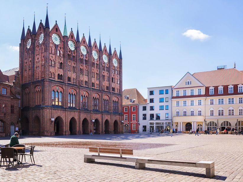 Das gotische Rathaus von Stralsund mit seiner markanten Backsteinfassade, umgeben vom historischen Marktplatz mit Kopfsteinpflaster und umliegenden Bürgerhäusern.