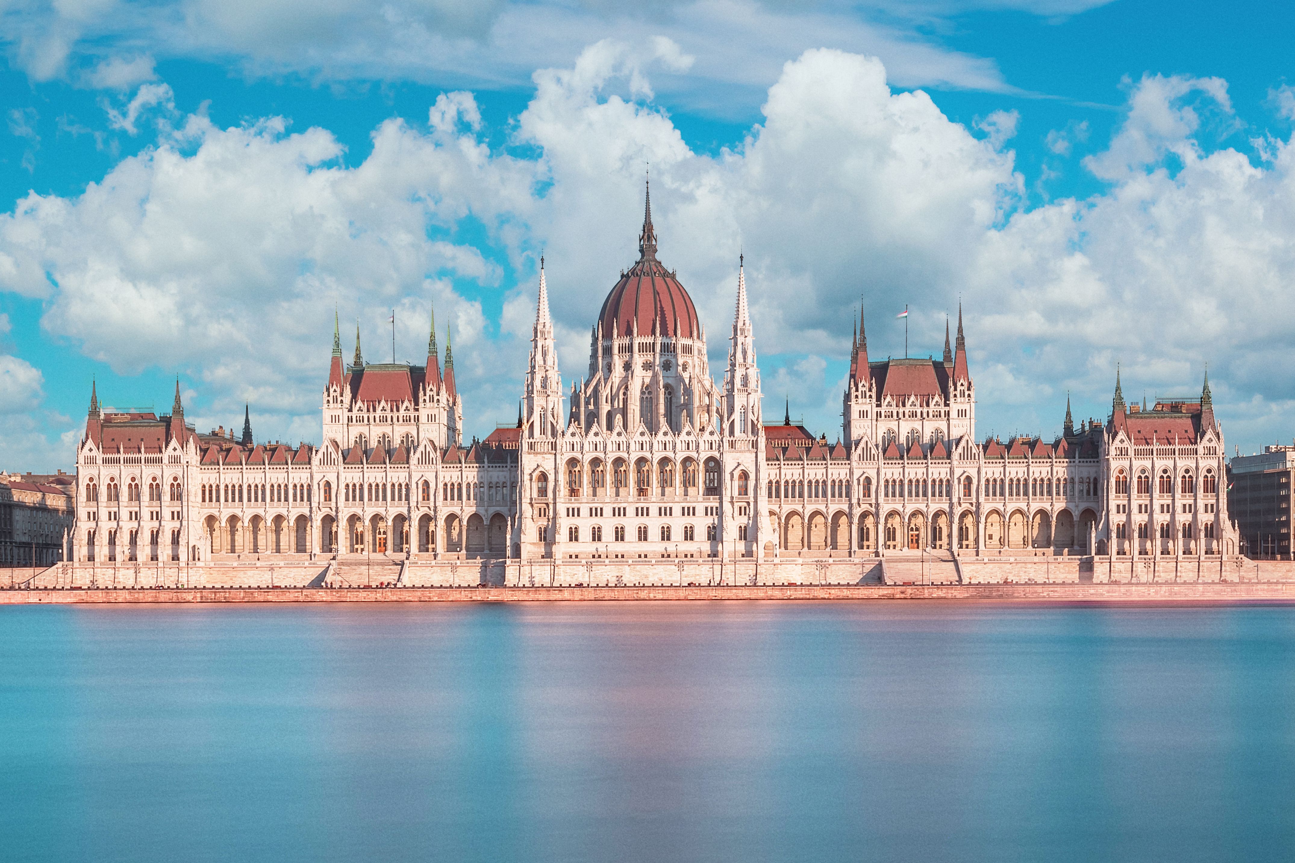 Parlamentsgebäude in Budapeste hinter Donau und mit blauem Himmel mit Wolken