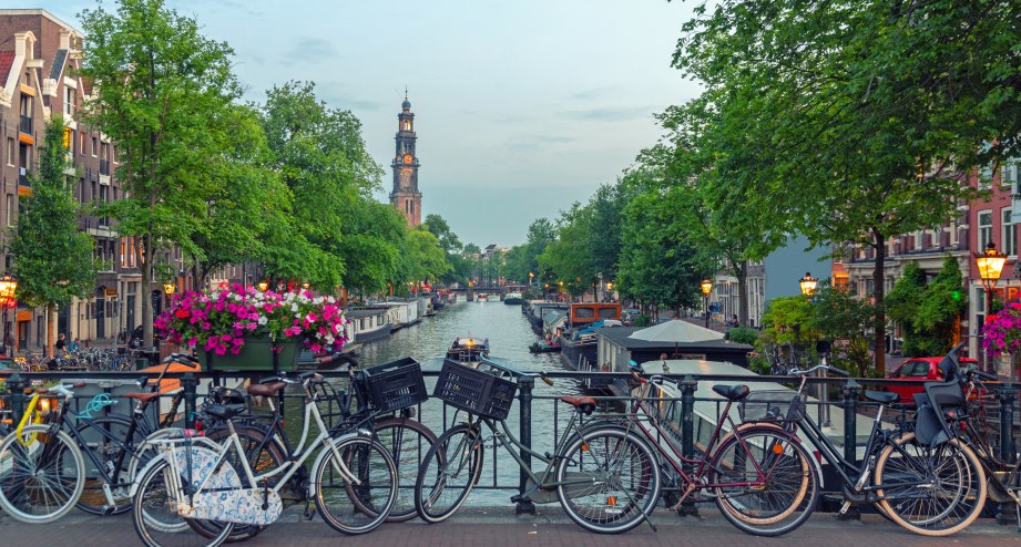 Grachtenbrücke mit Fahrrädern in Amsterdam bei Sonnenuntergang - BAHNHIT.DE, © getty, Foto: 2018 George Pachantouris