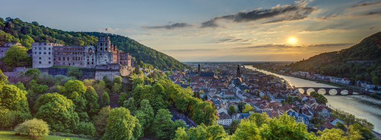 Aufnahme des Heidelberger Schlosses zwischen grünen Bäumen, Heidelberg ist im Hintergrund sichtbar - BAHNHIT.DE, © getty, Foto: Westend61
