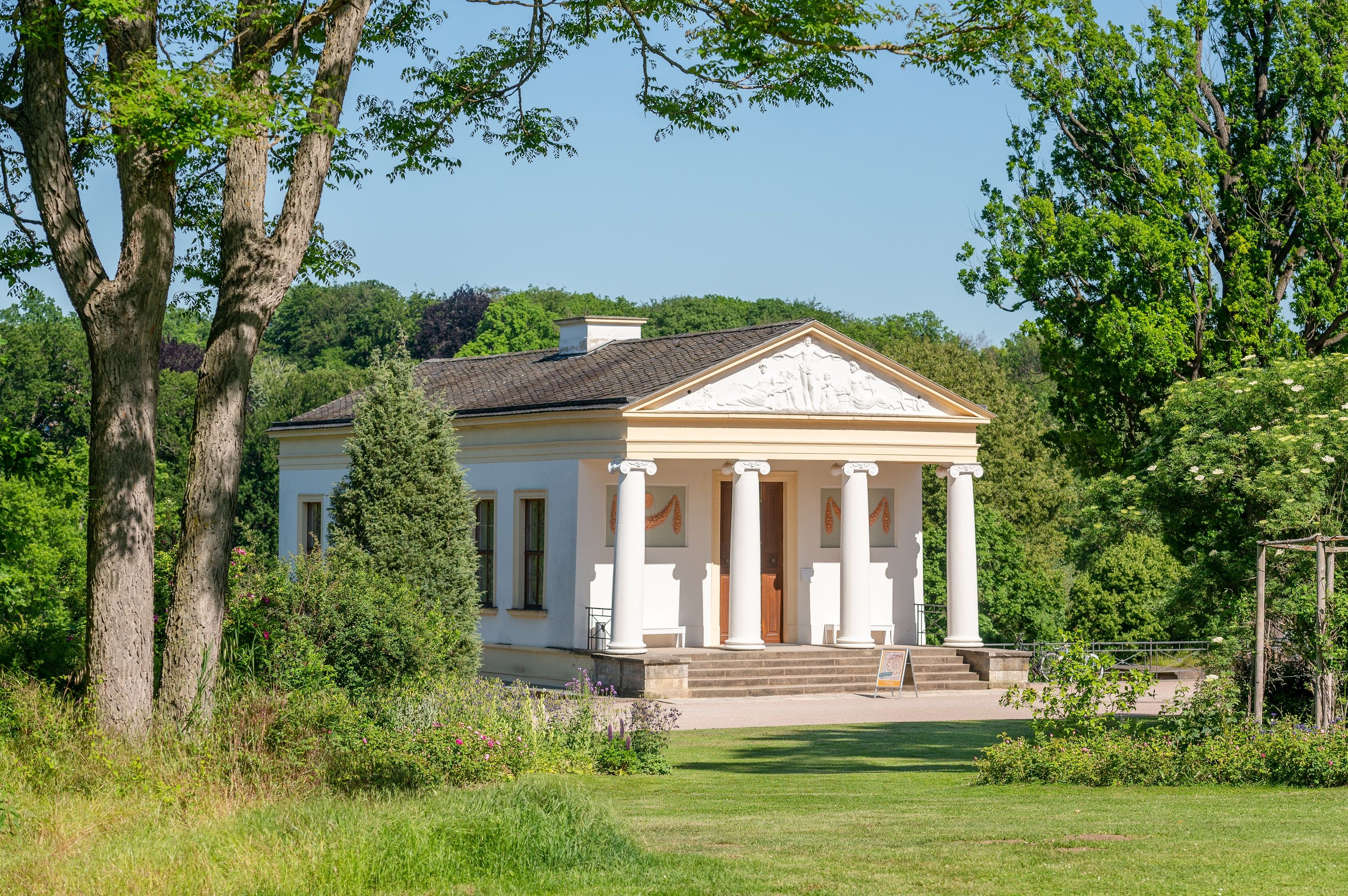 Das klassizistische Römische Haus im Park an der Ilm in Weimar, umgeben von altem Baumbestand und gepflegtem Grün, eingebettet in die natürliche Landschaft des Landschaftsparks.