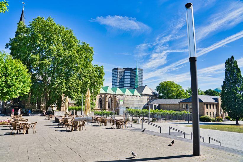 Stühle und Tische auf einem Platz vor dem Essener Dom bei Sonne