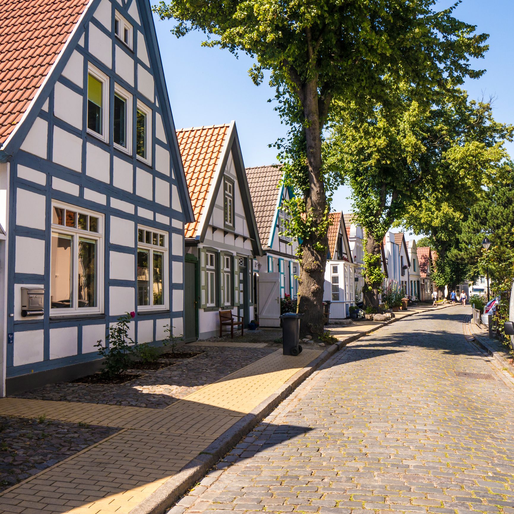 Kopfsteinpflasterstraße in Warnemünde mit traditionellen Fischerhäusern.