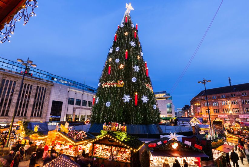 Großer Weihnachtsbaum mit Lichtern auf dem Dortmunder Weihnachtsmarkt, umgeben von Ständen.