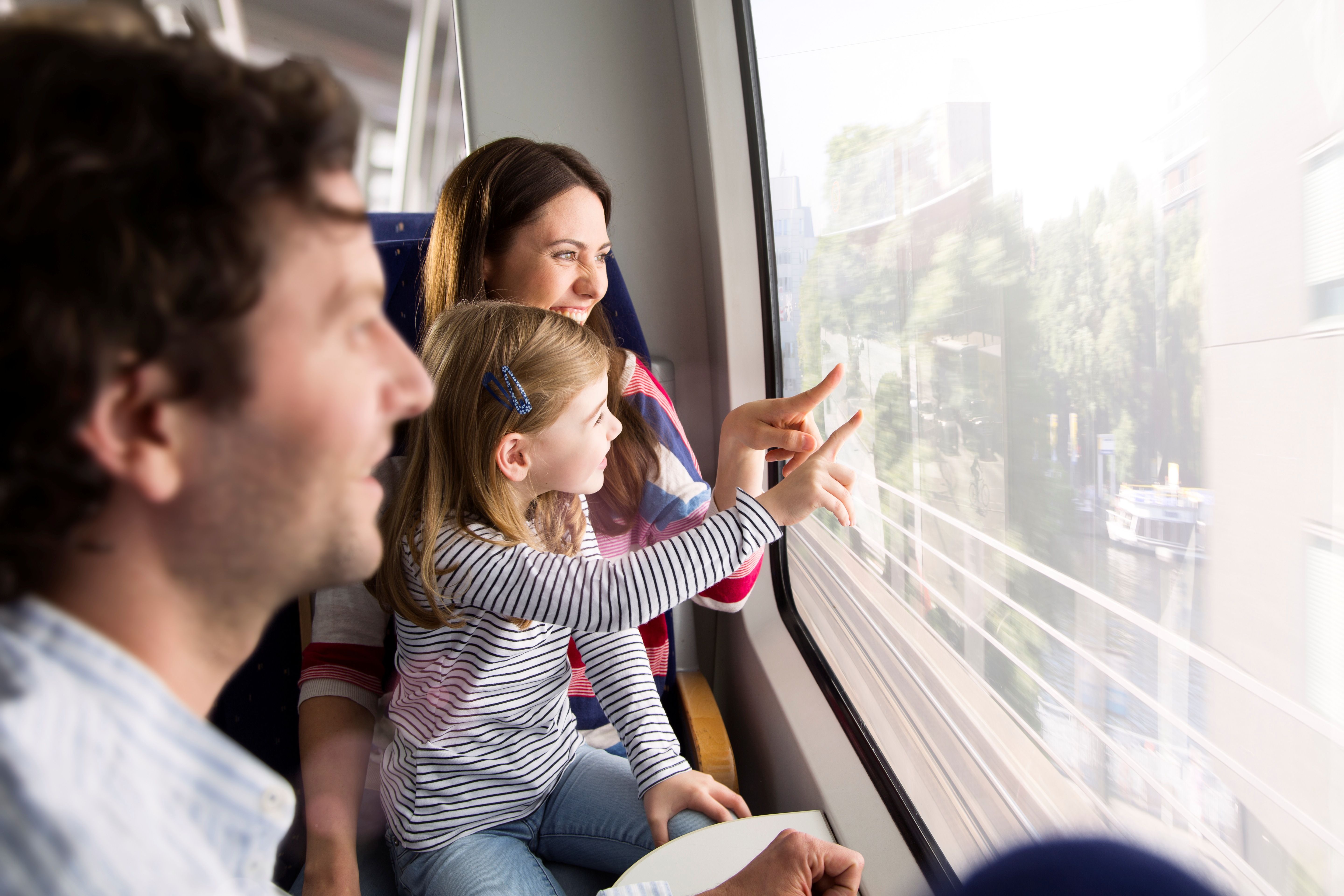 Familie mit einem kleinen Mädchen im Zug schauen aus dem Fenster