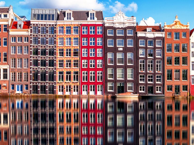 Blick auf eine Amsterdamer Gracht mit traditionellen Giebelhäusern entlang des Ufers.