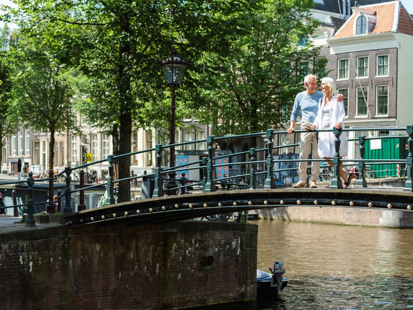 Ein Paar verweilt auf einer Amsterdamer Brücke und genießt die Aussicht auf die historische Gracht.