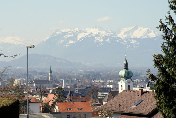 Im Vordergrund Dächer von Dornbirn und im Hintergrund Berge, die zum Teil mit Schnee bedeckt sind
