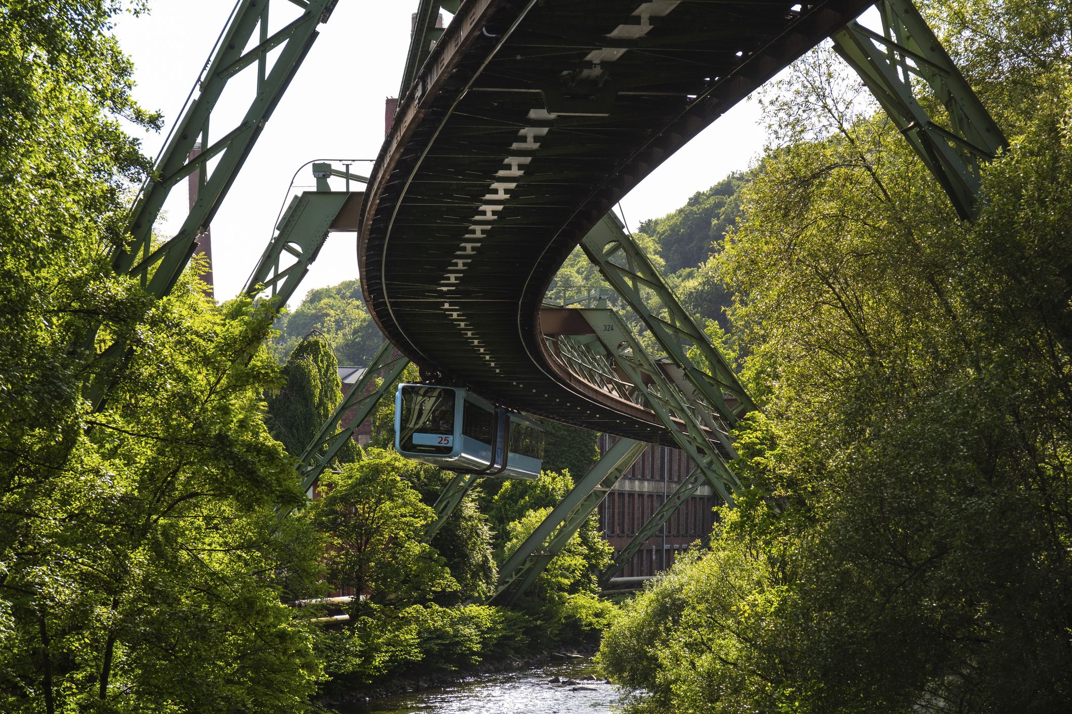 Wuppertaler Schwebebahn über dem Fluss Wupper umgeben von Grün