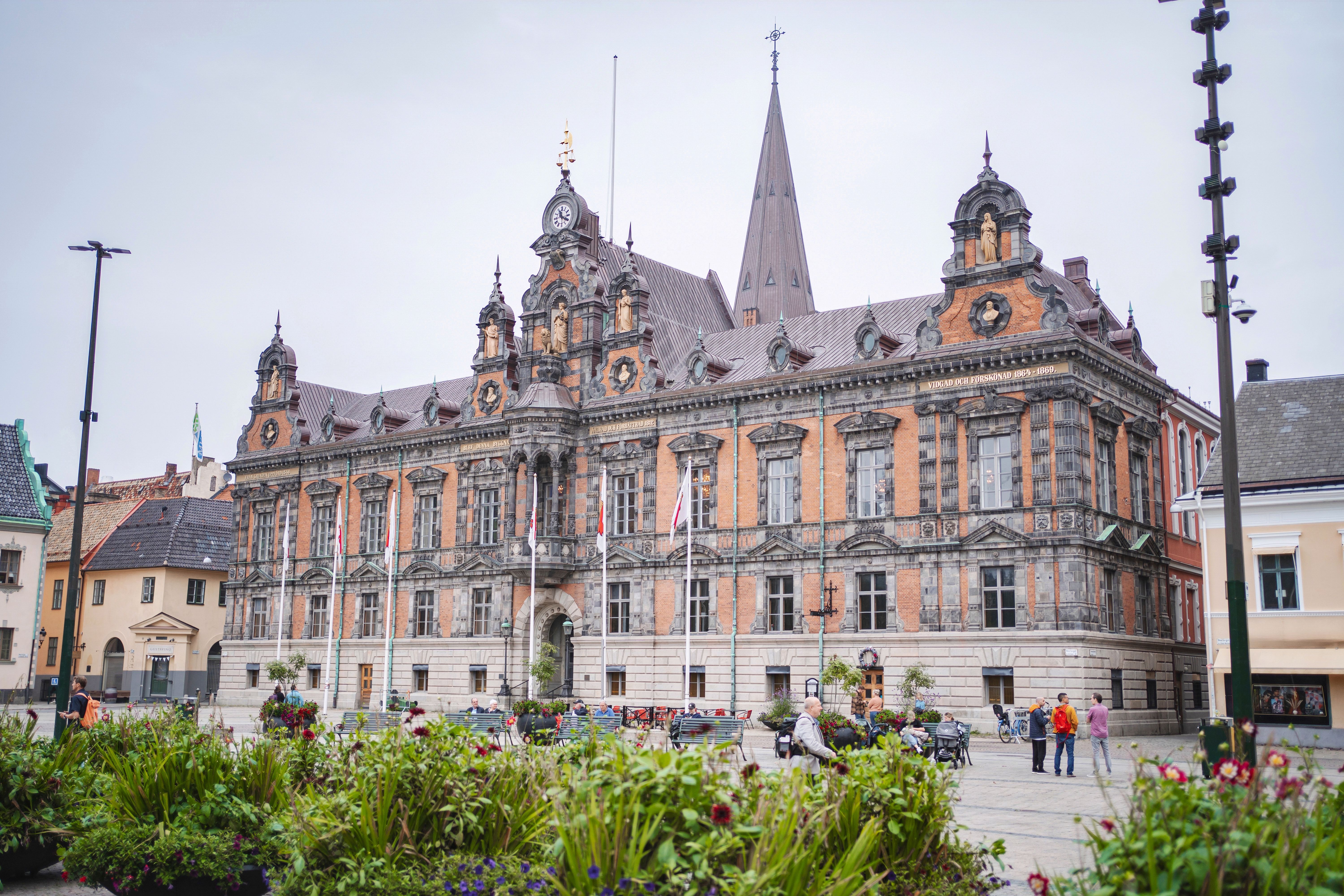 Blick auf das Rathaus von Malmö, im Vordergrund ein Beet mit Blumen, dahinter die historische Fassade.