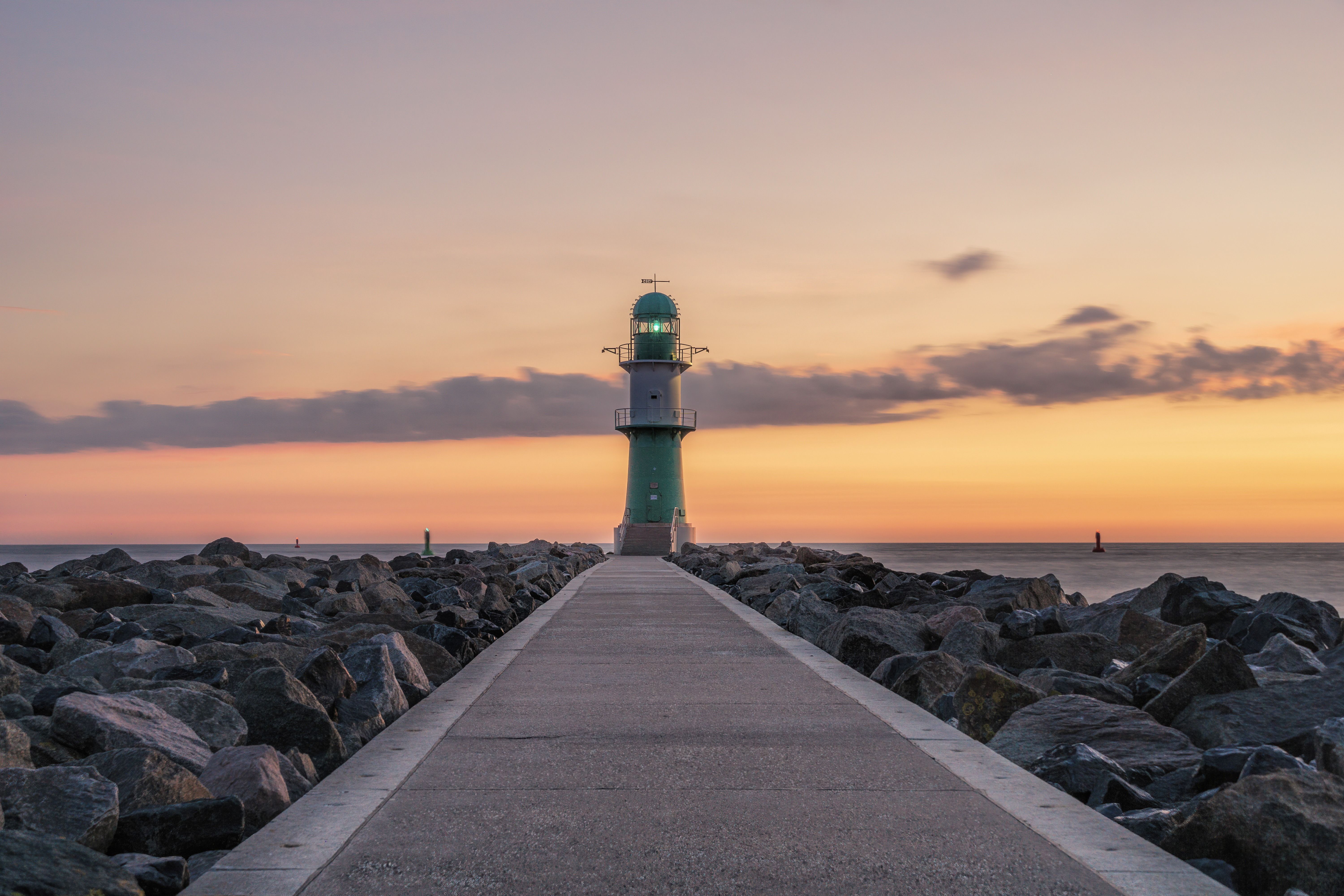 Leuchtturm Warnemünde bei Abenddämmerung vor lilafarbenem Himmel.