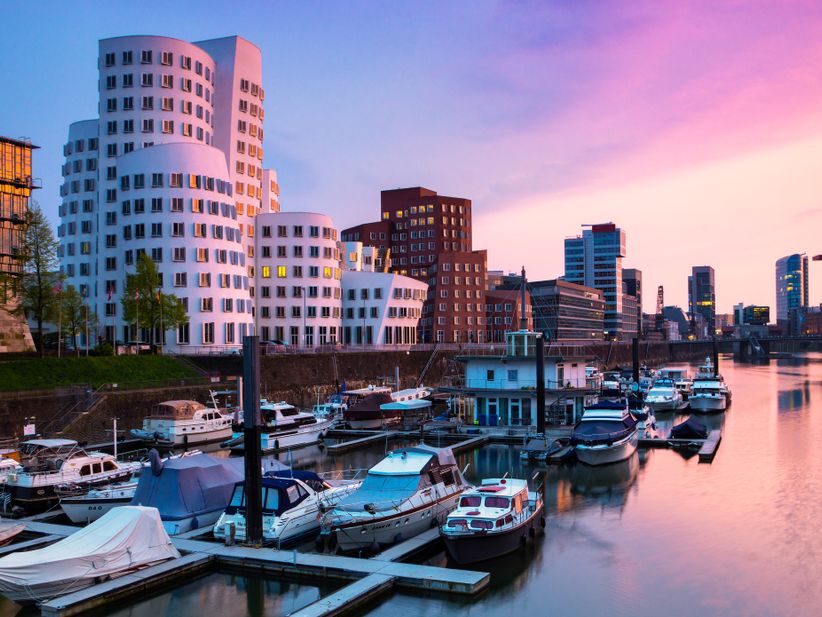 Blick auf den Düsseldorfer Hafen mit den tanzenden Häusern von Frank Gehry im Hintergrund bei pinkem Sonnenuntergang