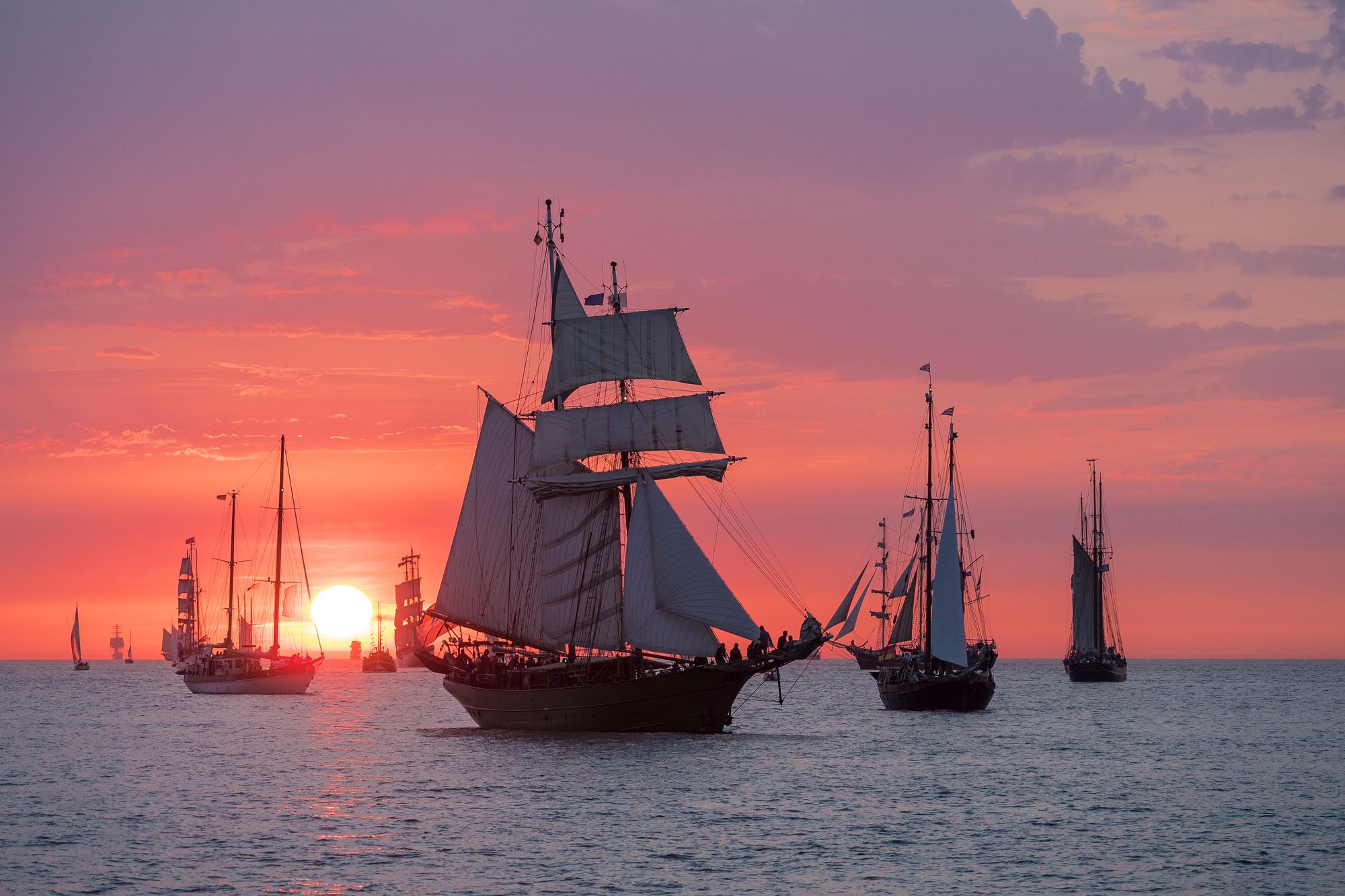 Mehrere historische Segelschiffe auf der Ostsee vor der Küste von Rostock bei ruhiger See.